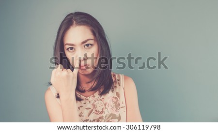 Picking nose. Vintage, retro style of portrait of Asian woman in pink vintage dress on blue - green background.