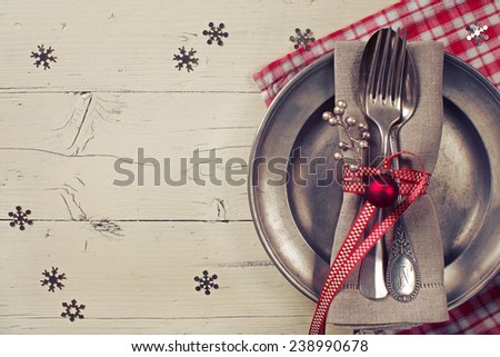 christmas table setting with vintage tin plate and silverware on a cream-colored table