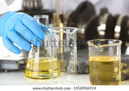 Male hands in protective gloves hold test tube in hands produces chemistry test of motor oil automatic gearbox and hydraulic booster