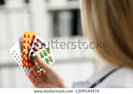 Female doctor hand holding pack of different tablet blisters at workplace closeup. Panacea life save service prescribe medicament legal drug store disease healing blood pressure concept