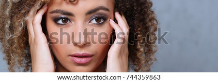 A beautiful black woman portrait. Tests the emotion of bewilderment of fear of terror confusion beauty fashion style mulatto curly hair with white locks eye view of the camera