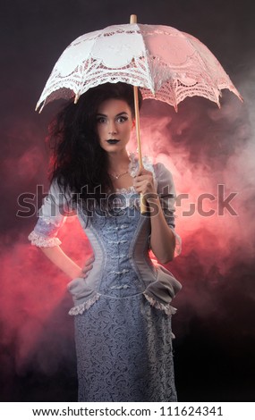 Surprised beautiful Halloween vampire woman aristocrat with lace-parasol