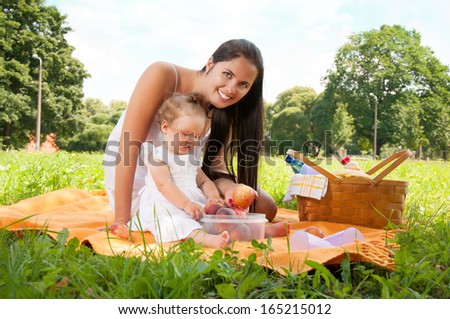 Young happy mother with daughter in the park picnicking