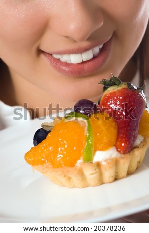 Young woman with low-calorie fruit cake (focus on face)