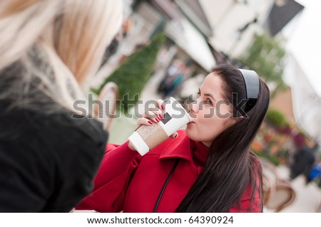 Two young women having coffee break together after shopping
