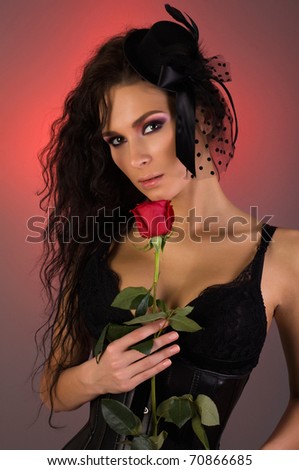 Portrait of young beautiful woman in little hat and rose in her hands.
