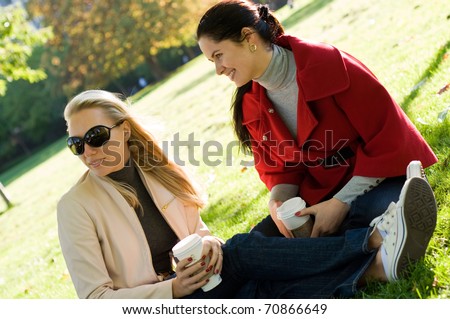 Two young women having coffee break together in park