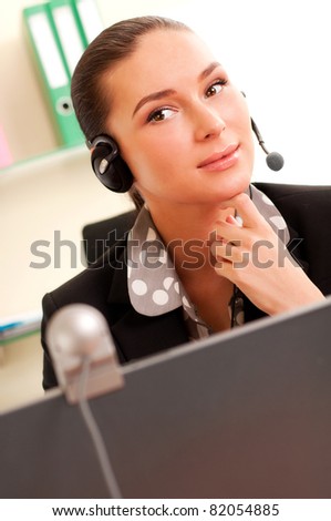 Young business woman working on computer and wearing headphones