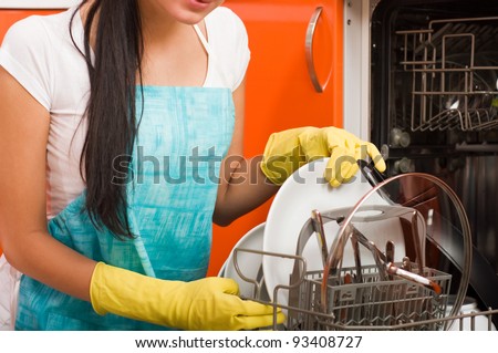Attractive brunette woman cleaning kitchen using dish washing machine.