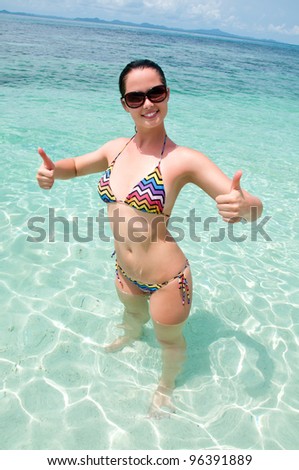 Happy smiling woman in sea water thumbs up