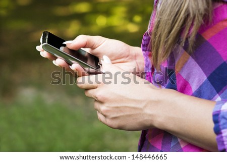 Mobile phone in hands. Closeup of female hands using a mobile phone, in the park