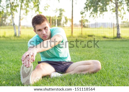Young male stretching. An attractive male stretching before his workout, outdoors