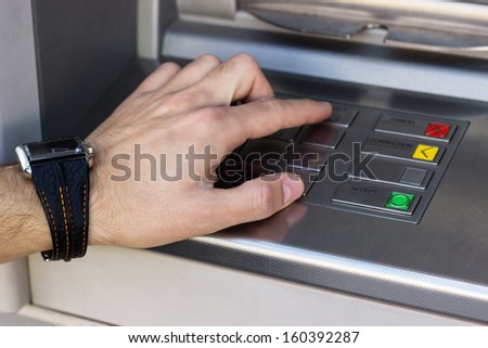 Hand entering personal identification number on ATM