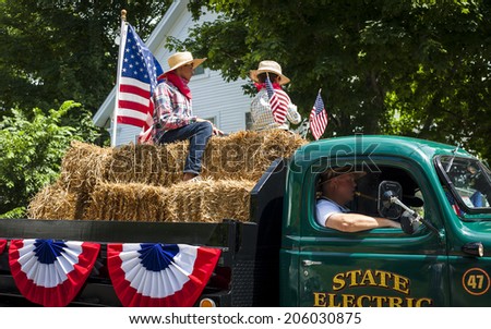 WOLFEBORO, NH - JULY 05, 2014: Children ride on hay bails in an antique truck for the annual Independence Day Parade.
