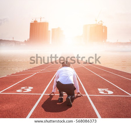 Business competition concept on track. Rear view of worker kneeling on the start line to city building. Motivation. Success.