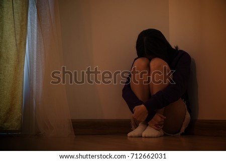 Teenager girl with depression sitting alone in the dark room. major depressive disorder.