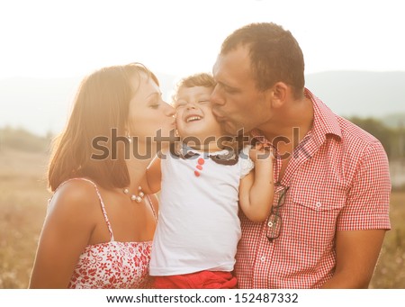 Happy mother, father and daughter in sunset.
