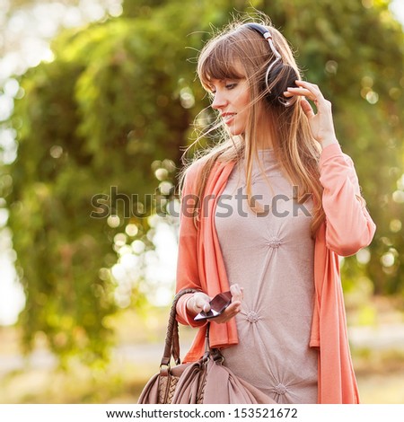 Young Beautiful Girl Listening To Mp3 Player On The Street