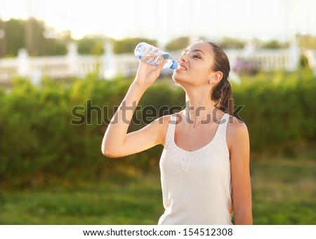 Portrait half face of young woman drink water bottle at summer green park