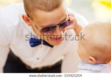 dad playing with his son, the son is played with sunglasses
