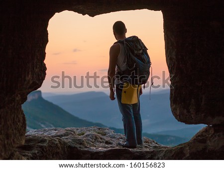 Silhouette of man with backpack in cave. Crimea.