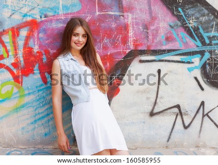 hipster girl outdoors stands near a graffiti wall