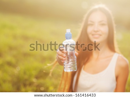Portrait half face of young woman holding water bottle at summer green park