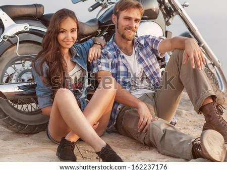 Two people and bike - fashion woman and man sitting by motorbike and resting. Adventure and vacations concept