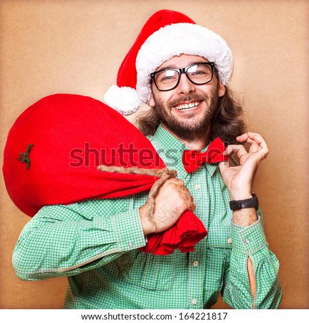 Santa Claus with a bag of gifts looking at the camera and holding his bow tie