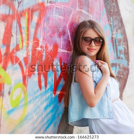 Hipster Girl Outdoors Stands Near A Graffiti Wall