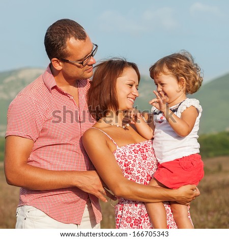Happy mother, father and daughter in  the mountains at sunset