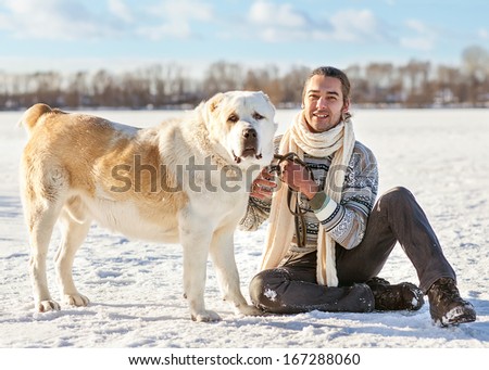 Man and central Asian shepherd walk in the park