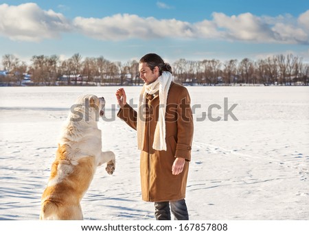 Man and central Asian shepherd playing with his dog outdoors