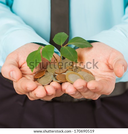 Businessman cover growing plant with coin money