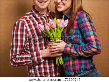 Valentine\'s day. Man and woman holding a bouquet of tulips in hands. Hipster Style. studio shot