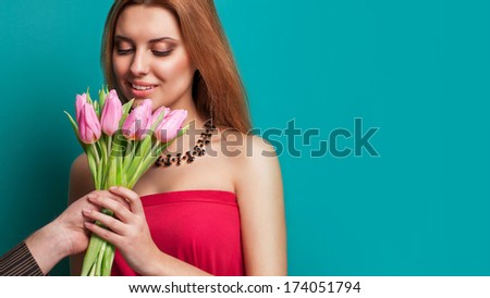 Young beautiful girl gives a bouquet of tulips man, holding out his hand with a bouquet. Celebrating valentine