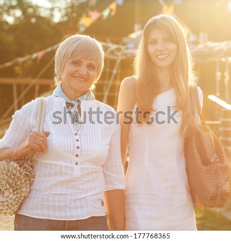 Adult mother and daughter after shopping walk down the street and talk