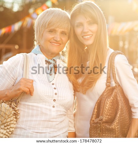 Adult mother and daughter after shopping walk down the street and talk