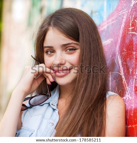 girl outdoors stands near a graffiti wall