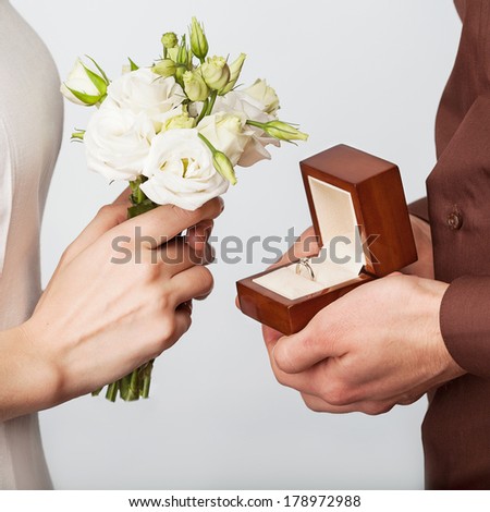 Wedding couple holding ring box and a bouquet of flowers