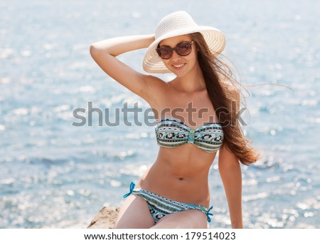 Woman sitting on the beach turned wistfully looking at the sky in the background