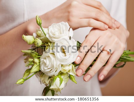 Woman with beautifully manicured purple nails holding a handful of whitei flower petals