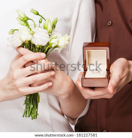 Wedding couple holding ring box and a bouquet of flowers
