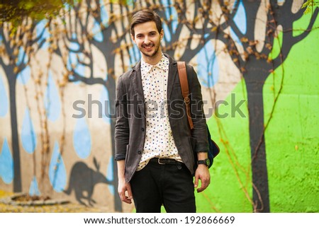 attractive young male model posing on green wall outdoors