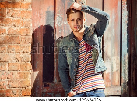 Hipster style guy. Fashion man standing near  a wooden door