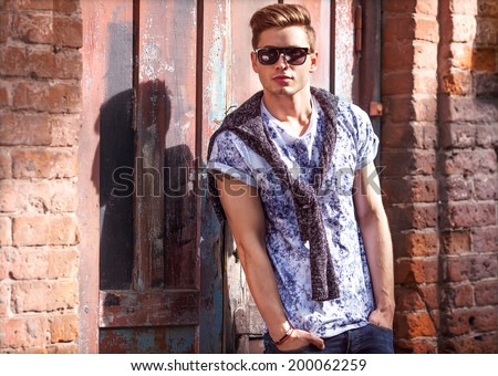 Hipster style guy. Fashion man standing near a wooden door