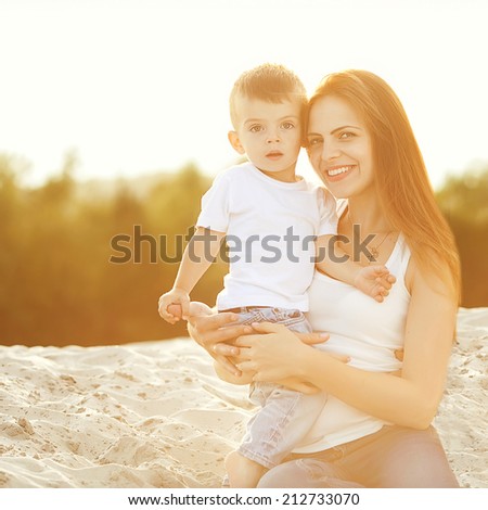 Happy mother and son on the beach sunset