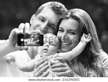 Family with baby In Park  taking selfie by mobile phone