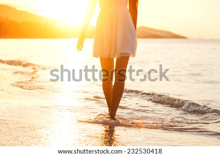 Beautiful girl walking on the beach at sunset, freedom concept