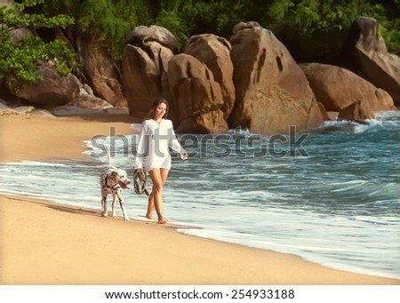 girl walk on the beach with the dog Dalmatian